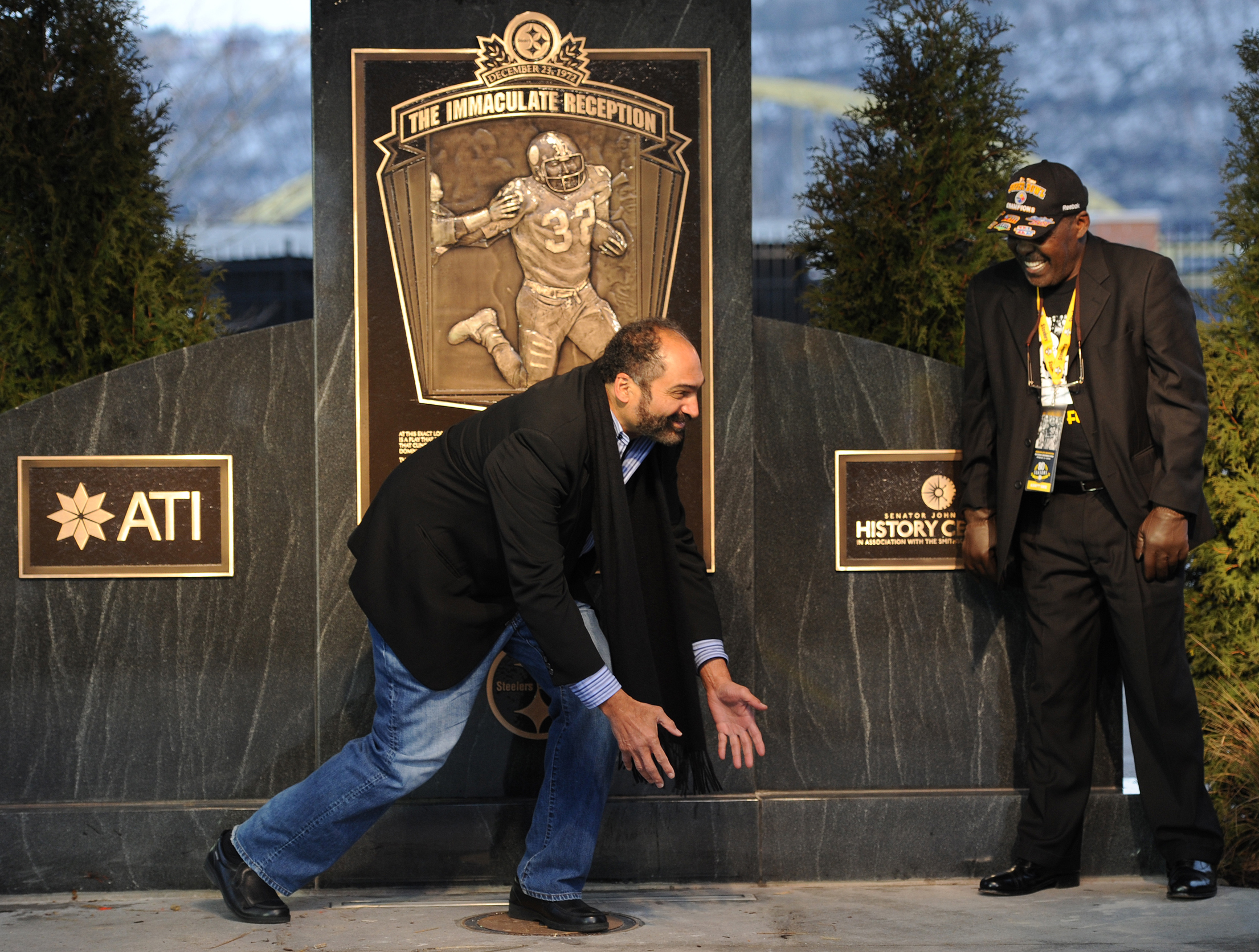 Franco Harris demonstrates the Immaculate Reception as John Frenchy Fuqua looks on at the unveiling of a historical marker designating the spot where the the play occurred on the North Side on Saturday, December 22, 2012. (Rebecca Droke/Post-Gazette)