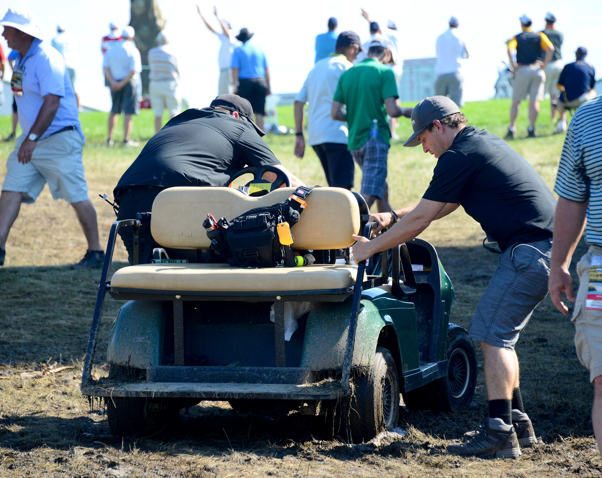 Grounds crew members try to free a cart from the mud Friday ay Oakmont Country Club. (Lake Fong/Post-Gazette)