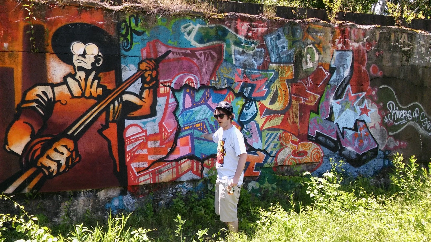 Shane Pilster, graffiti artist, graphic designer, and urban arts coordinator for the Rivers of Steel National Heritage Area, in front of a graffiti mural at the Carrie Furnace site. (Lake Fong/Pittsburgh Post-Gazette)