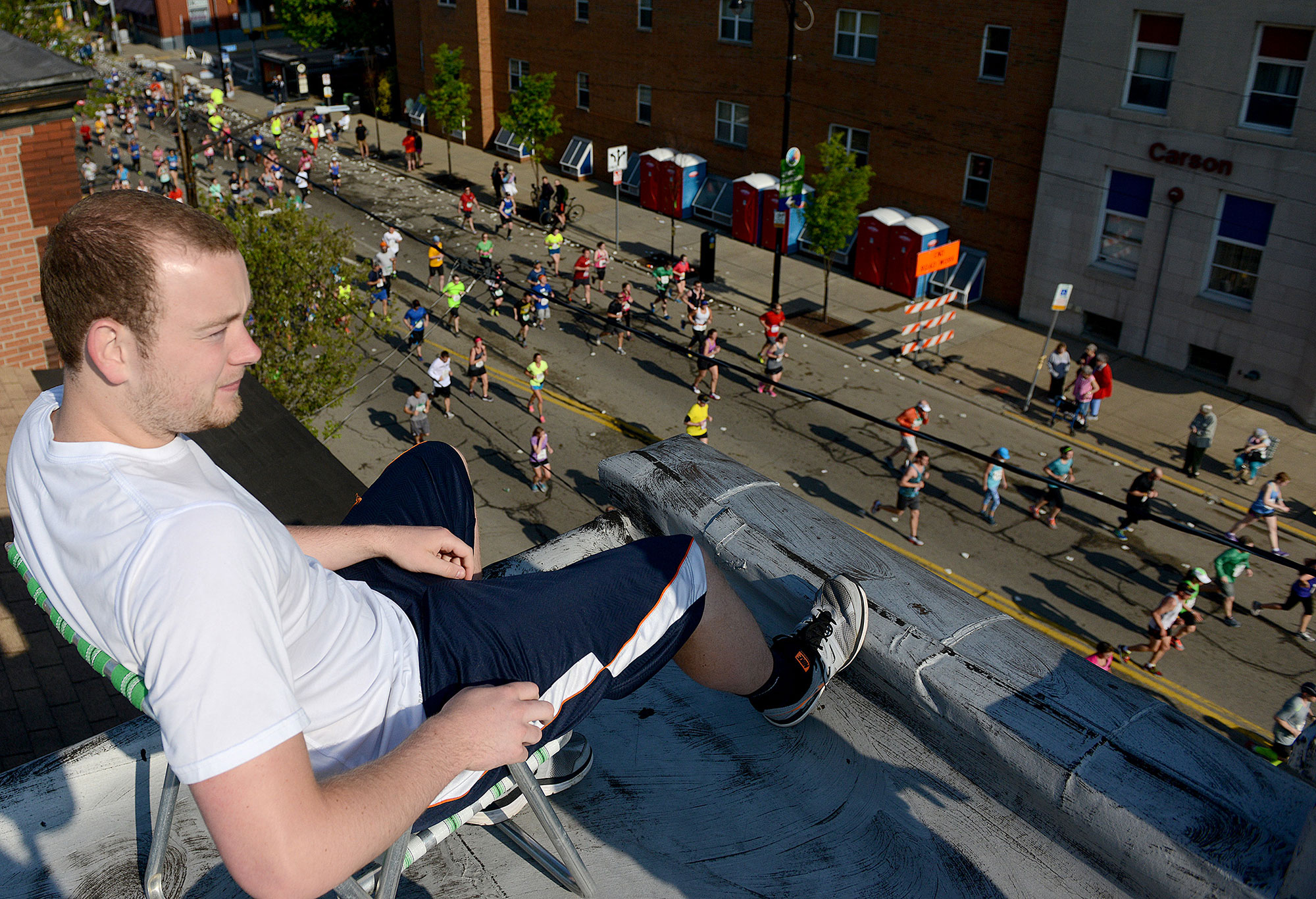 Chad Nowak of the South Side watches from the roof of an apartment building on Carson Street. (Michael Henninger/Post-Gazette)