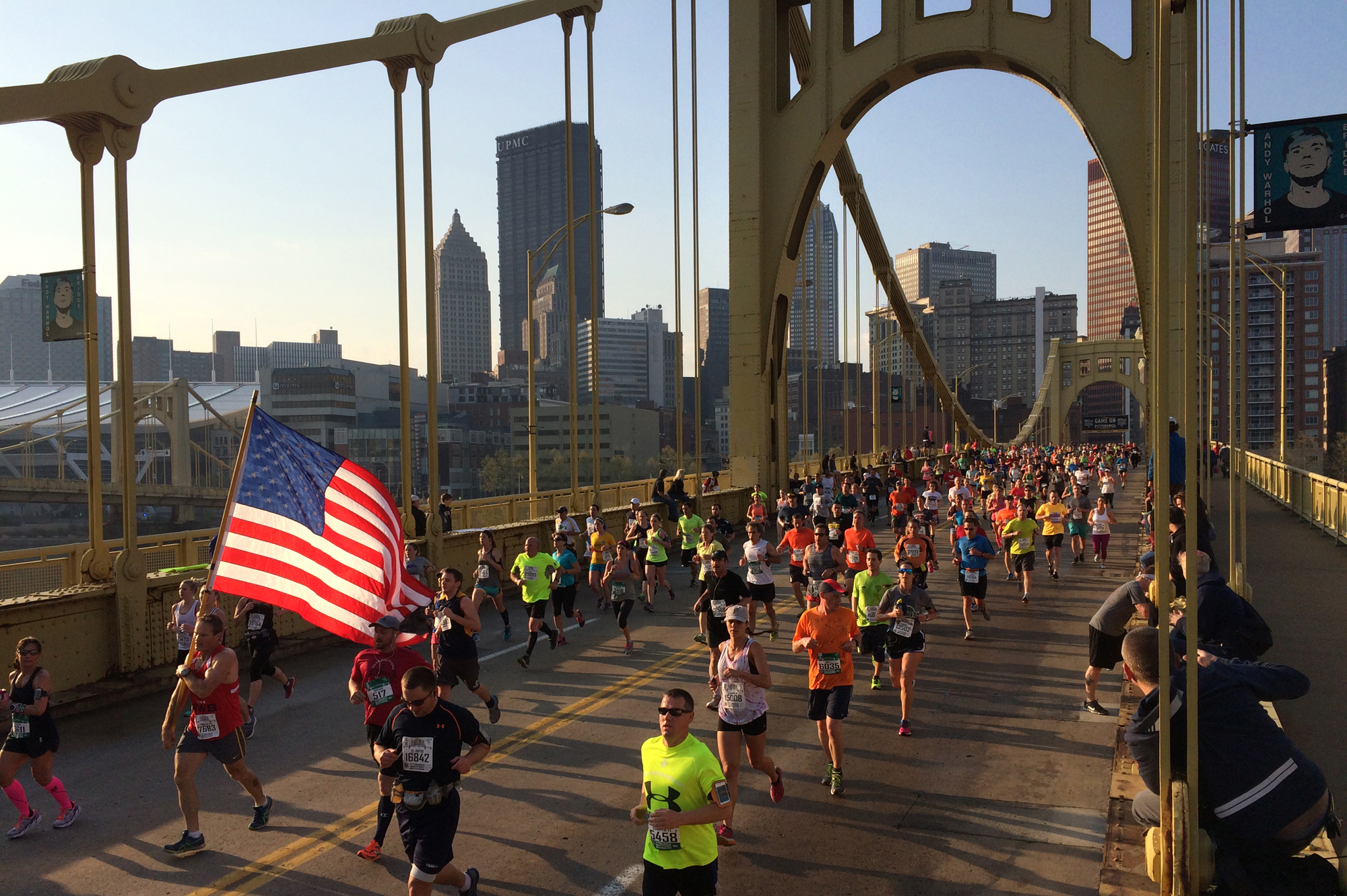 A flag-waving runner makes his way across the Andy Warhol Bridge. (Steve Mellon/Post-Gazette)