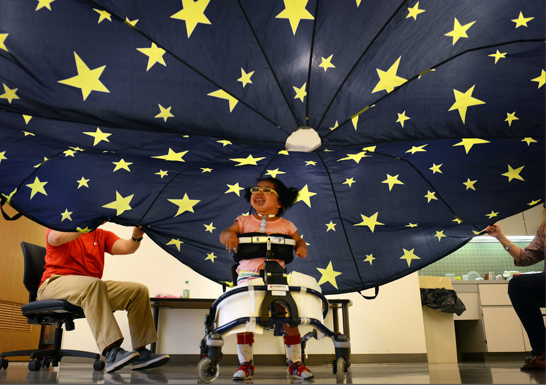 Adapted physical education teacher Ben Brimyer lifts a parachute over the head of Giana James, 5, during class at the Western Pennsylvania School for Blind Children in Oakland on Aug. 26, 2015. The students use the parachute as a basic activity that gives them a sensory reward for following directions, Mr. Brimyer said. (Julia Rendleman/Post-Gazette)